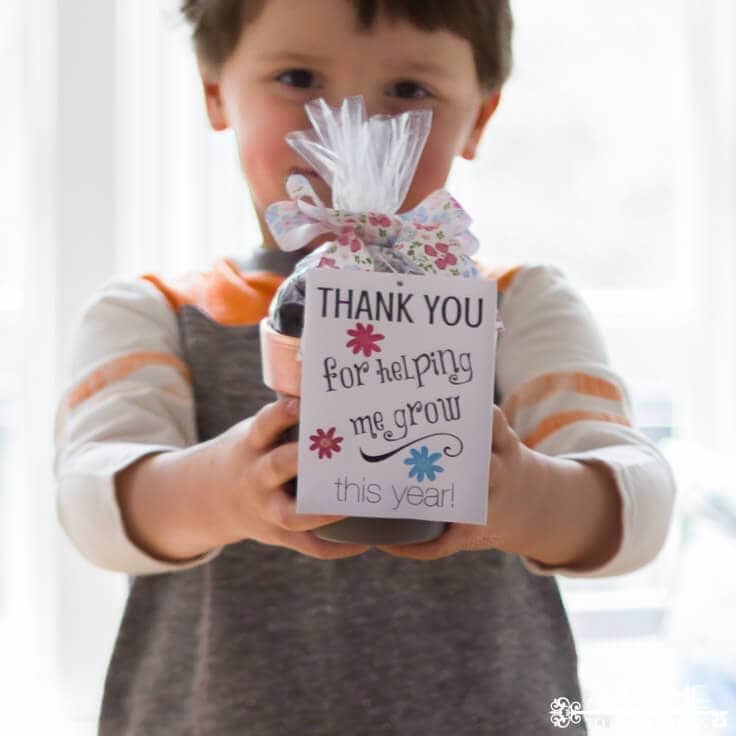 Child holding a potted plant with a tag that reads 