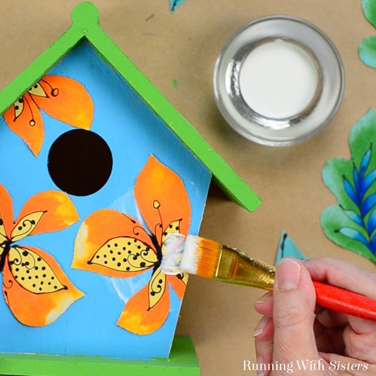 Gluing fabric flowers on the birdhouse