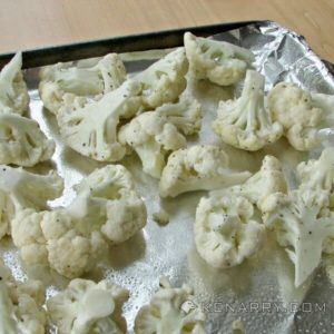 cauliflower pieces on an aluminum foil lined baking sheet