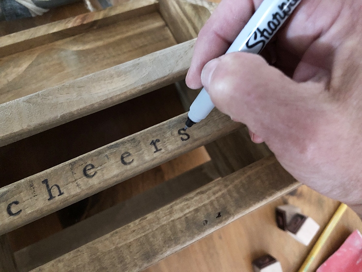 Use a permanent black marker to fill in the letters and make them darker on the wood. 