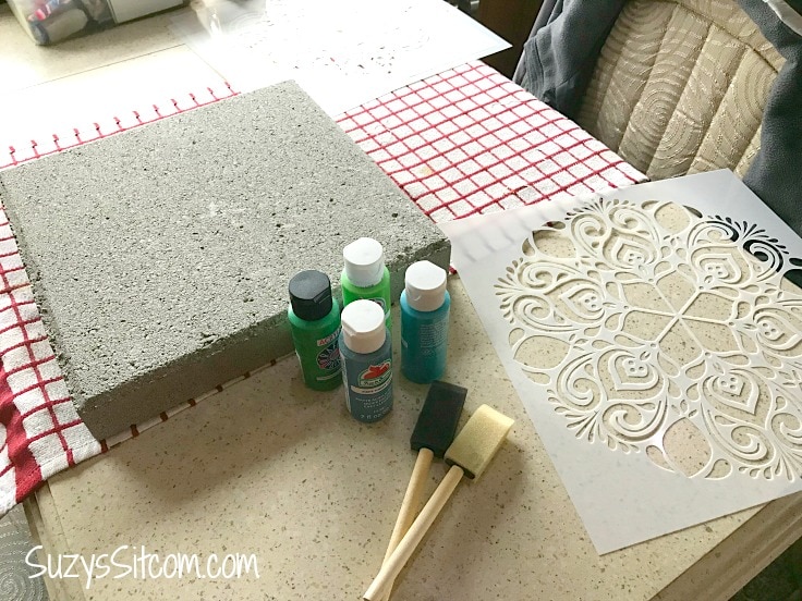 Paint, brushes, a cement stepping stone and a stencil