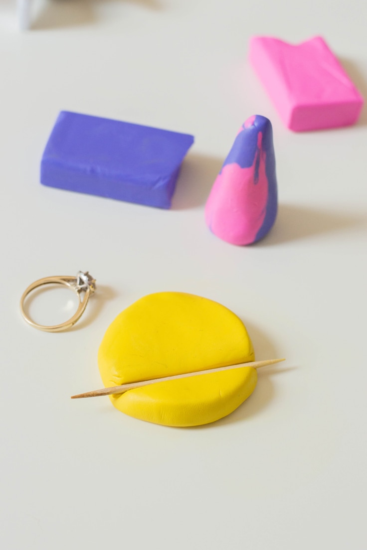 A toothpick making an indention in yellow polymer clay. This will be used in a DIY ring holder