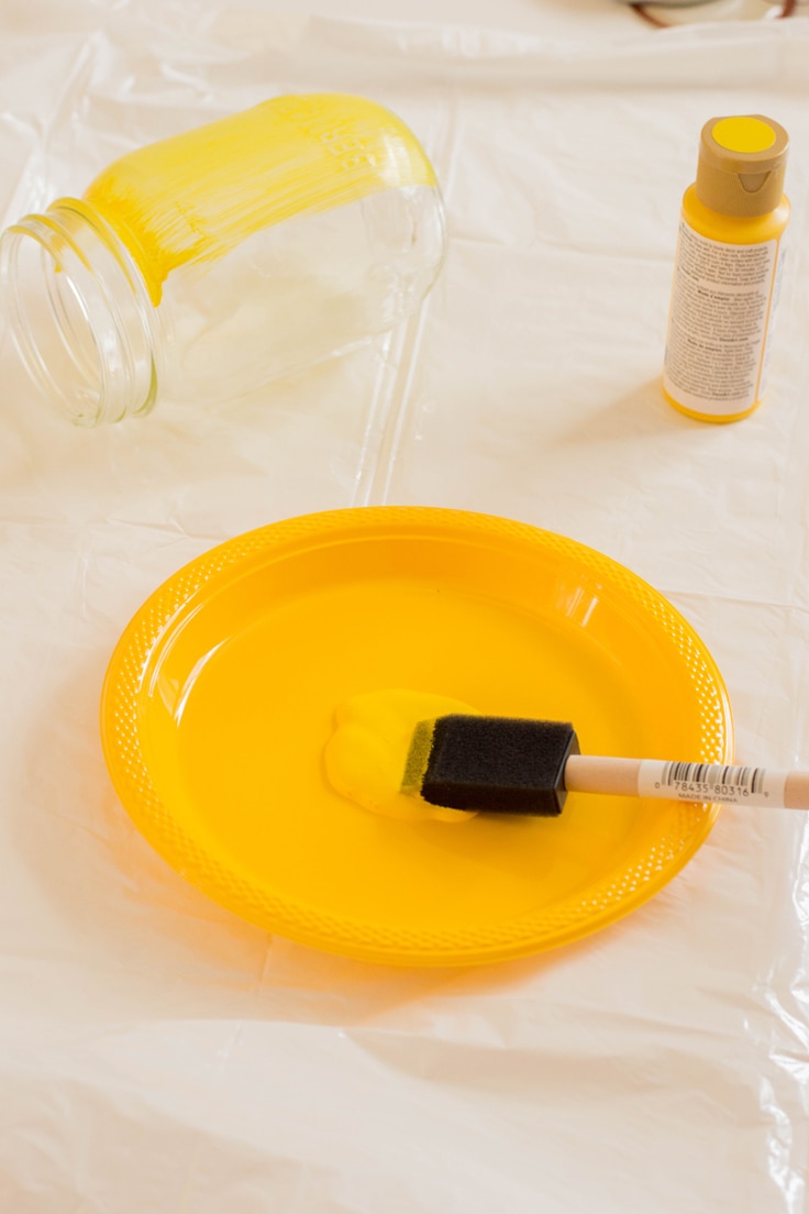 Painting a mason jar yellow with a foam brush