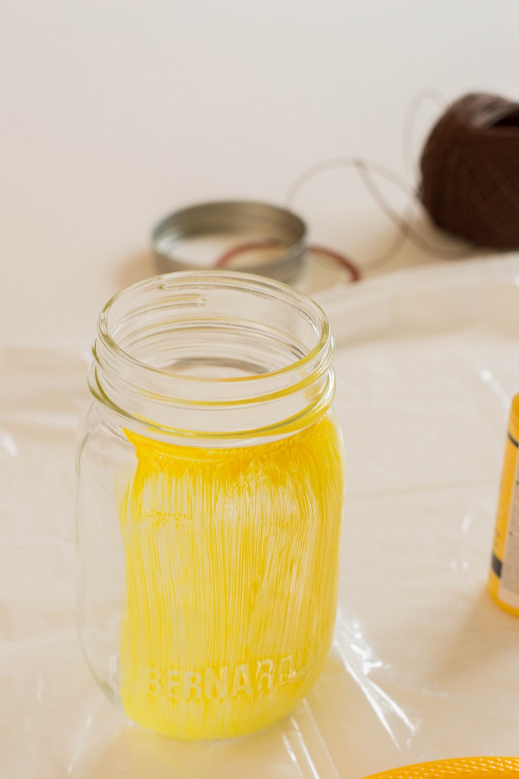 A mason jar with some yellow paint on it. 