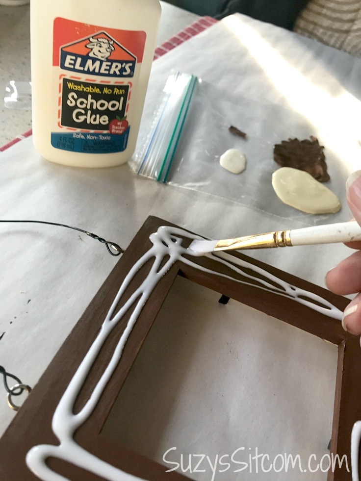Spreading white glue on a brown-painted picture frame