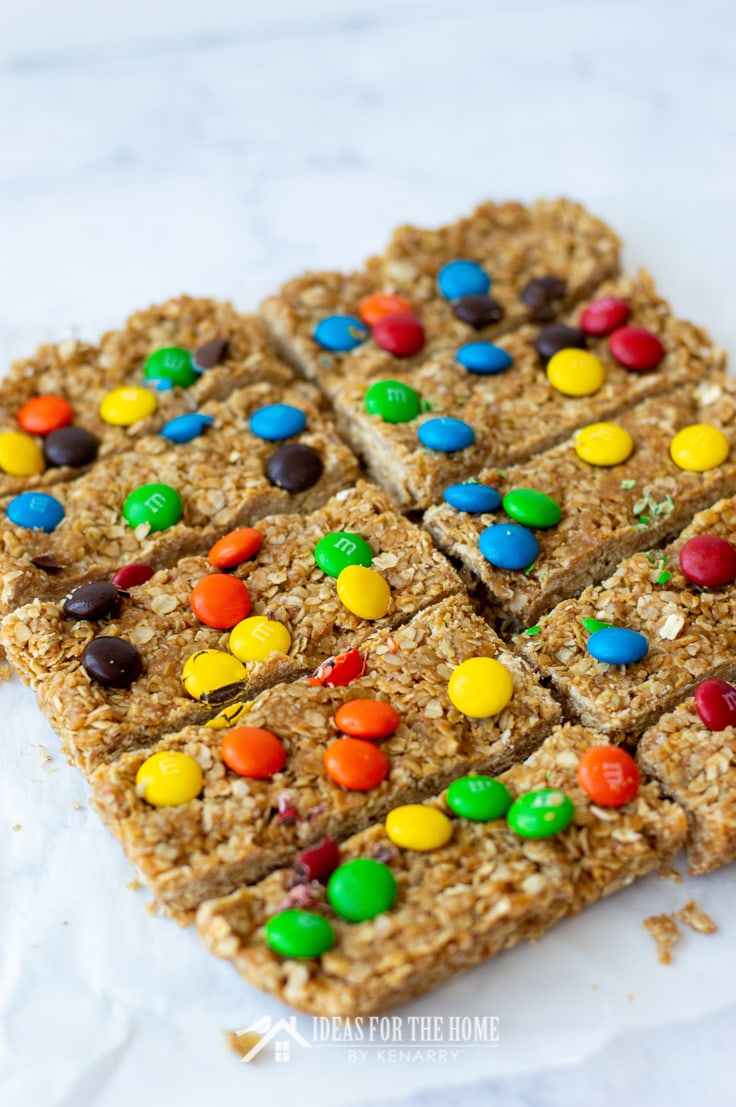 Granola bars on parchment paper. These treats are fresh out of the pan and sliced into ten separate granola bars as after school snacks for kids.