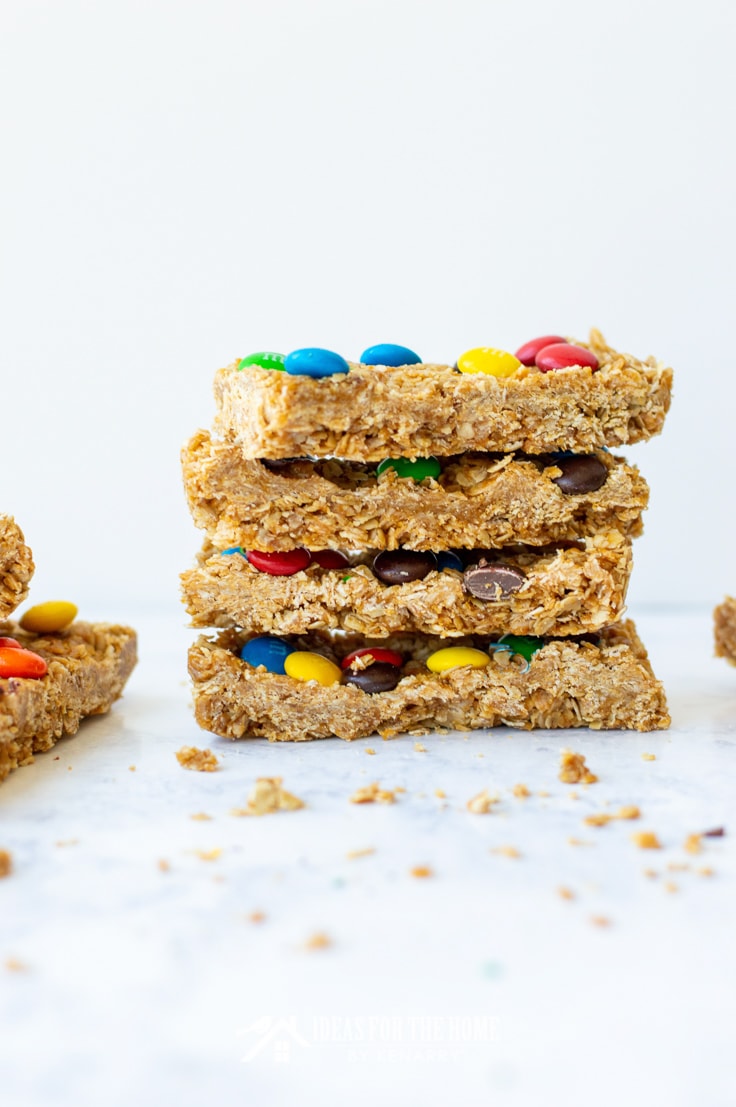 Four M&M granola bars stacked on top of one another with oat crumbs
