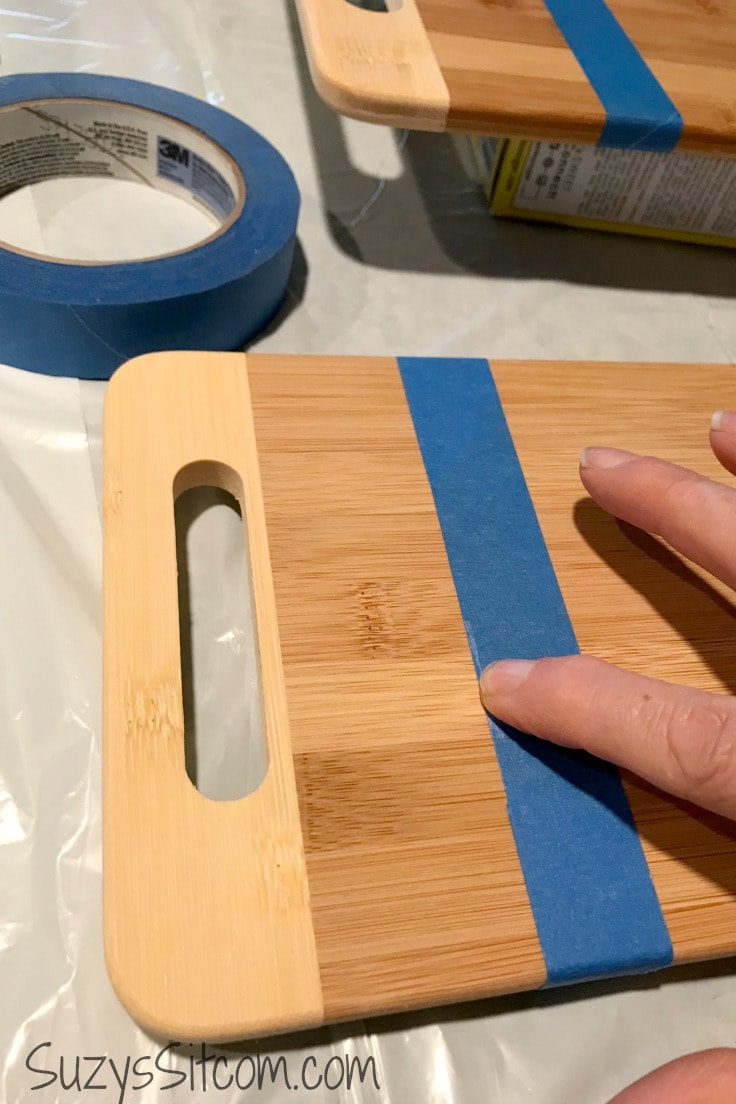 Putting blue painter's tape on a wood cutting board. 