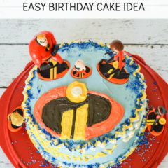 Incredibles Easy Birthday Cake Idea, overhead view of a round double layer cake with the Incredibles 2 logo on top surrounded by toy action figures from the popular Disney animated movie