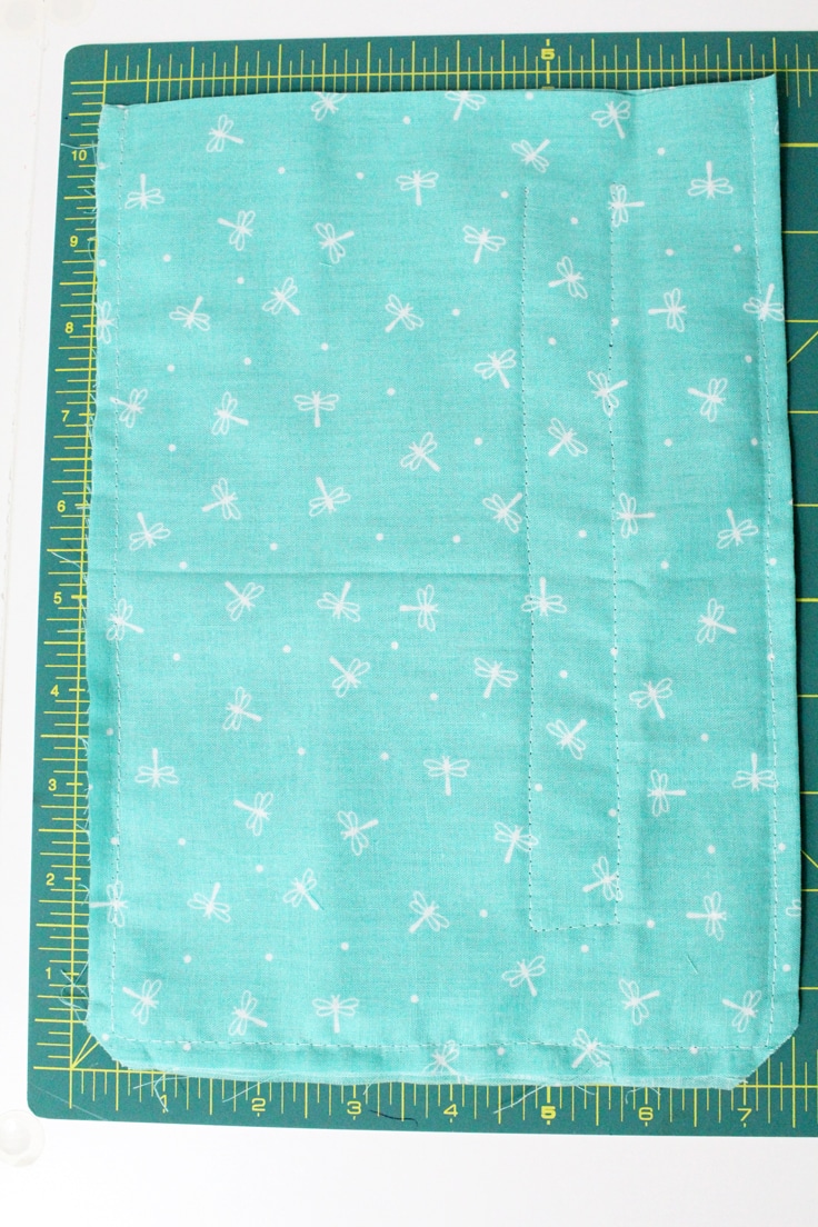blue rectangle of fabric hemmed on 3 sides with the outline of a pocket