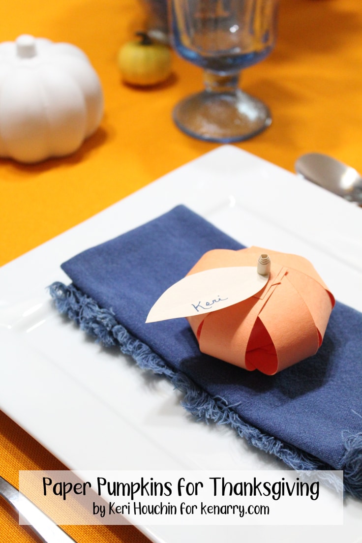 orange paper pumpkin with a name written on the leaf sitting on a napkin and plate