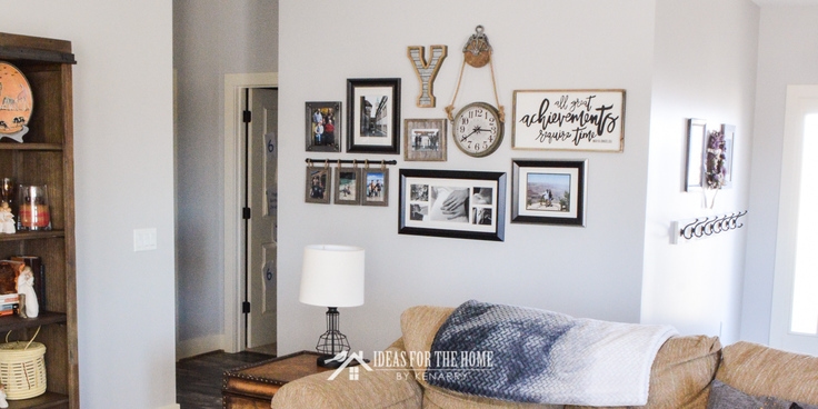 A family photo gallery wall behind a sectional sofa as farmhouse style home decor in a living room