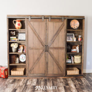 A television is hidden behind sliding barn wood doors on this farmhouse entertainment center.