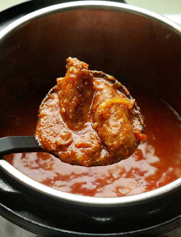 A big ladle full of sausage, peppers and marinara sauce. 