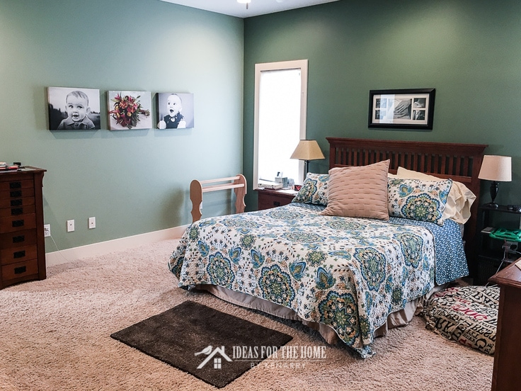 Sage green master bedroom with dark green accent wall behind a queen sized mission style bed