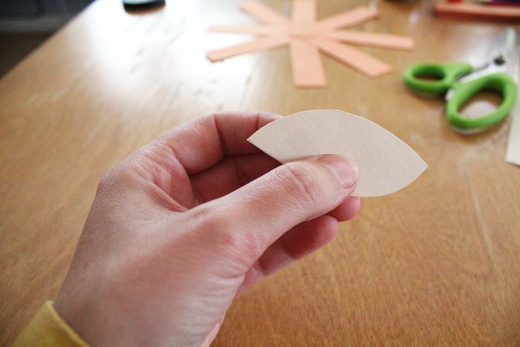 a hand holding a manila paper leaf shape