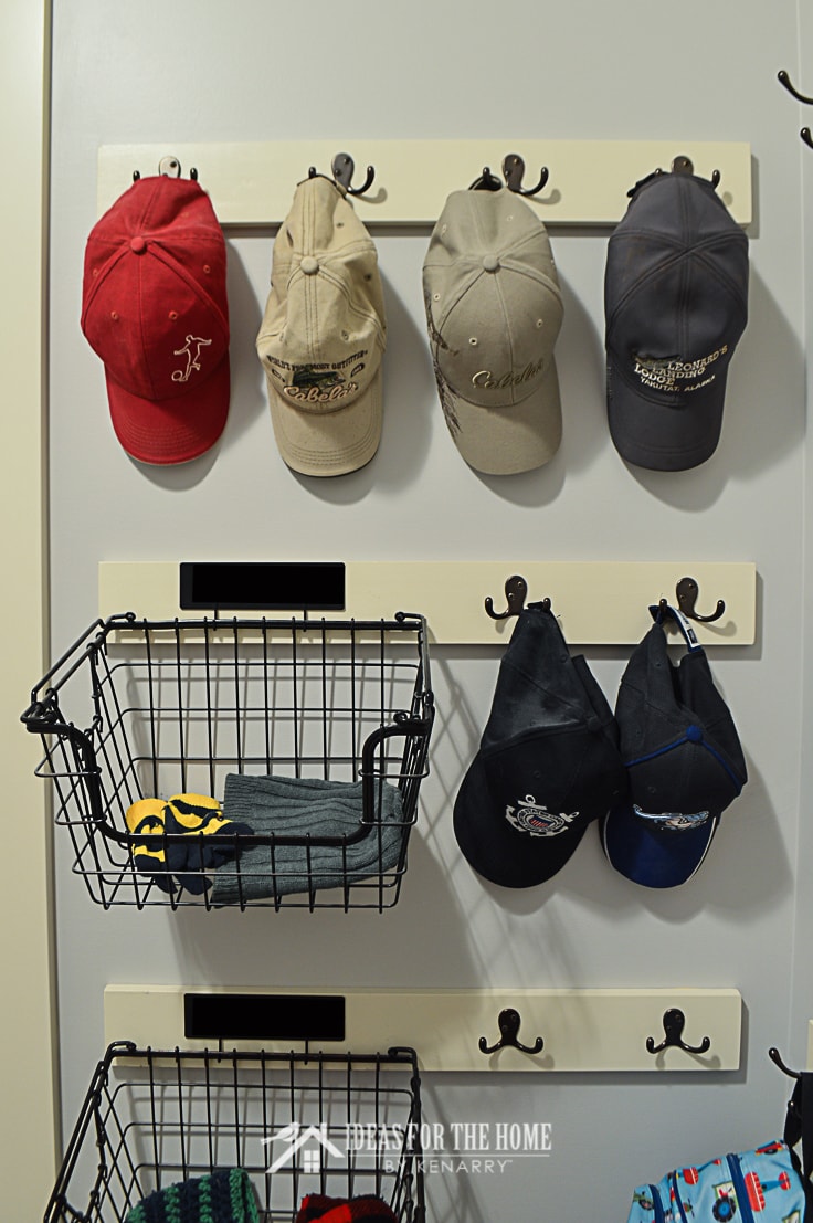 Hooks used to hold baseball hats alongside wire baskets for winter hats and mittens help to organize a mudroom