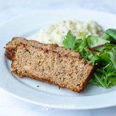 Two slices of barbecue turkey meatloaf on a plate with mashed potatoes and salad