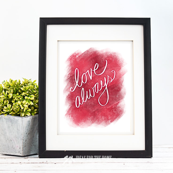 Love Always Valentine's Day print in a black frame next to a small potted plant