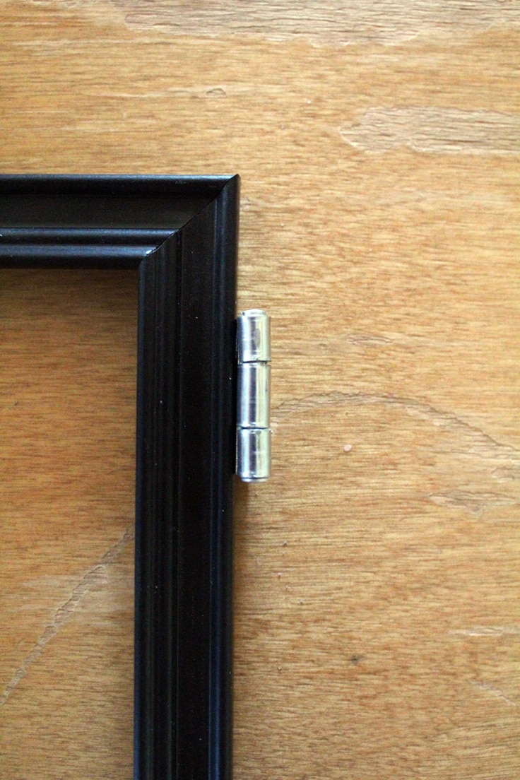 Closeup of a metal hinge on the right corner of a photo frame. This one faces the opposite direction from the one above.
