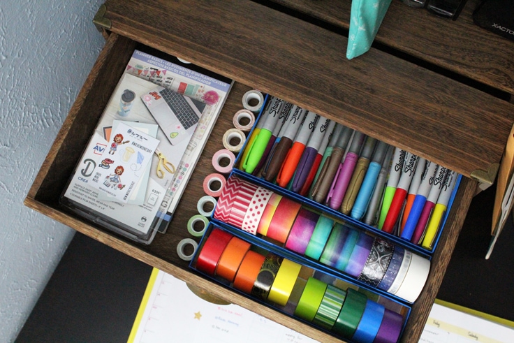an organized wooden drawer showing paper drawer organizers to separate pens, tape, and stickers