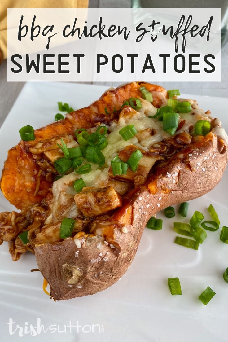 Baked sweet potato stuffed with chicken topped with cheese & green onions on a white plate.