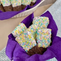 Vanilla Dipped Chocolate Graham Crackers covered in sprinkles on a purple napkin.