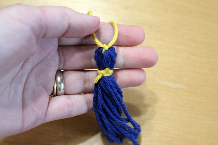 hand holding a blue yarn tassel