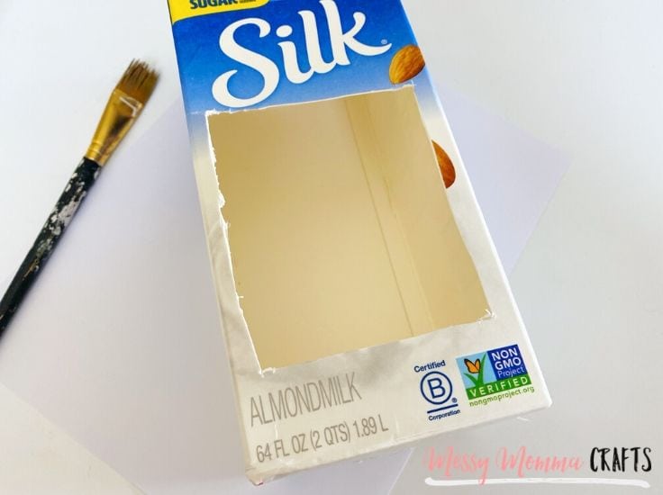 Carefully use a utility knife to cut a opening for the birds on one side of the milk carton.