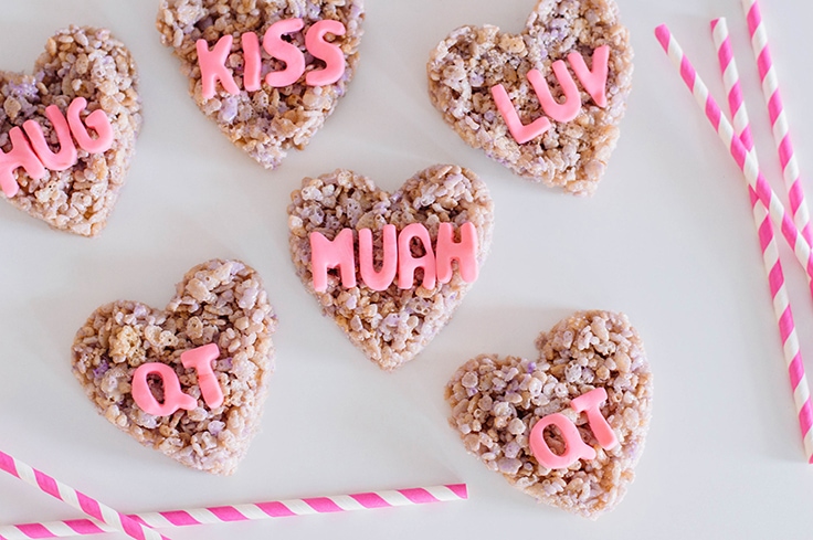 Rice cereal treats that are shaped like hearts and have conversation heart writings on them. 