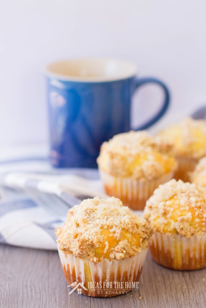 4 lemon muffins with a cup of coffee in the background
