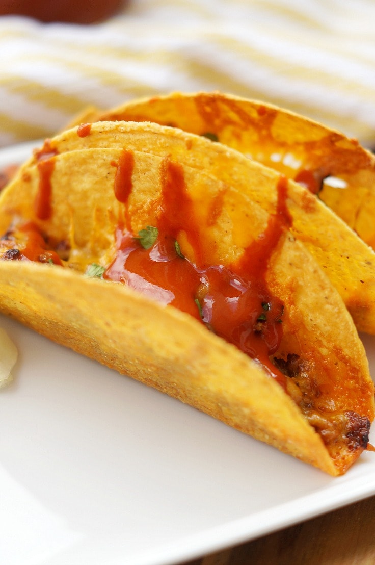 A close up of beef tacos with taco sauce 