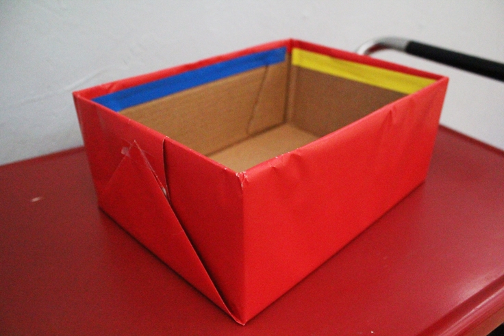 a cardboard box covered in red gift wrap