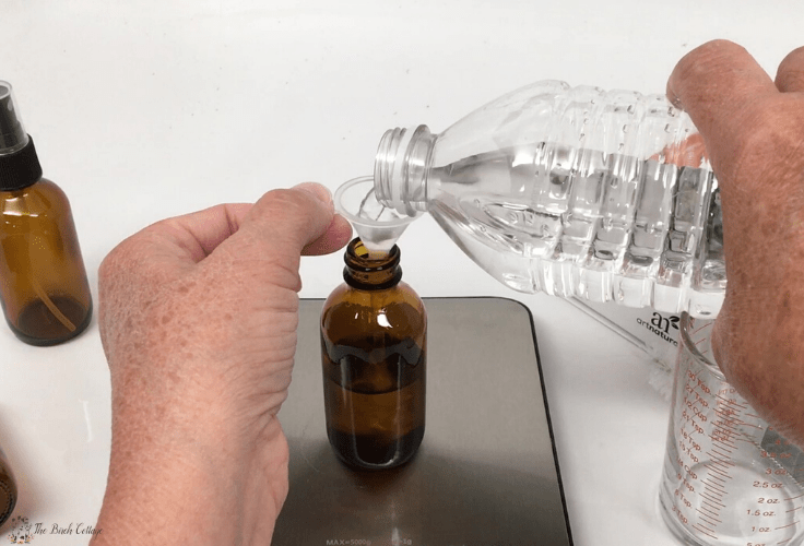 pouring distilled water through funnel into glass amber bottle