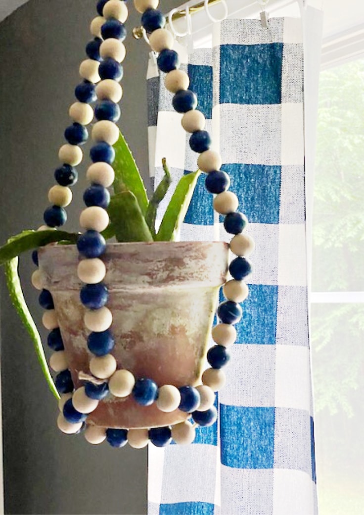 wood bead hanging planter with aloe plant hanging in window