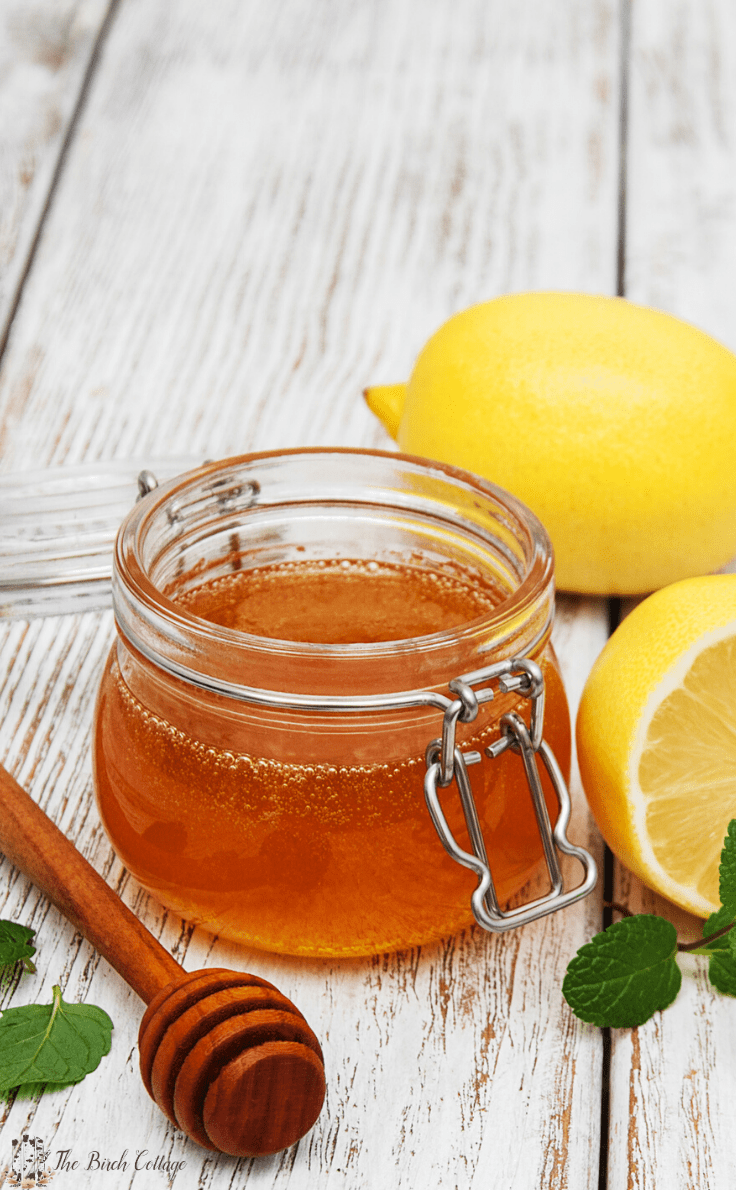 Weck jar of honey with honey dipper and lemons