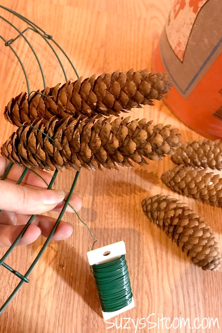 Attaching pine cones to a wreath form.