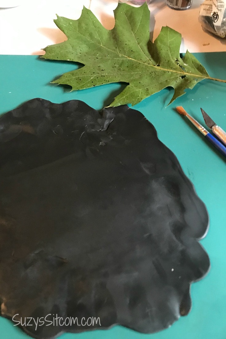 a green leaf next to some black polymer clay 