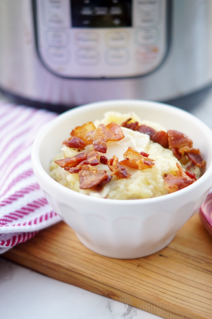 A white bowl of mashed potatoes with bacon 