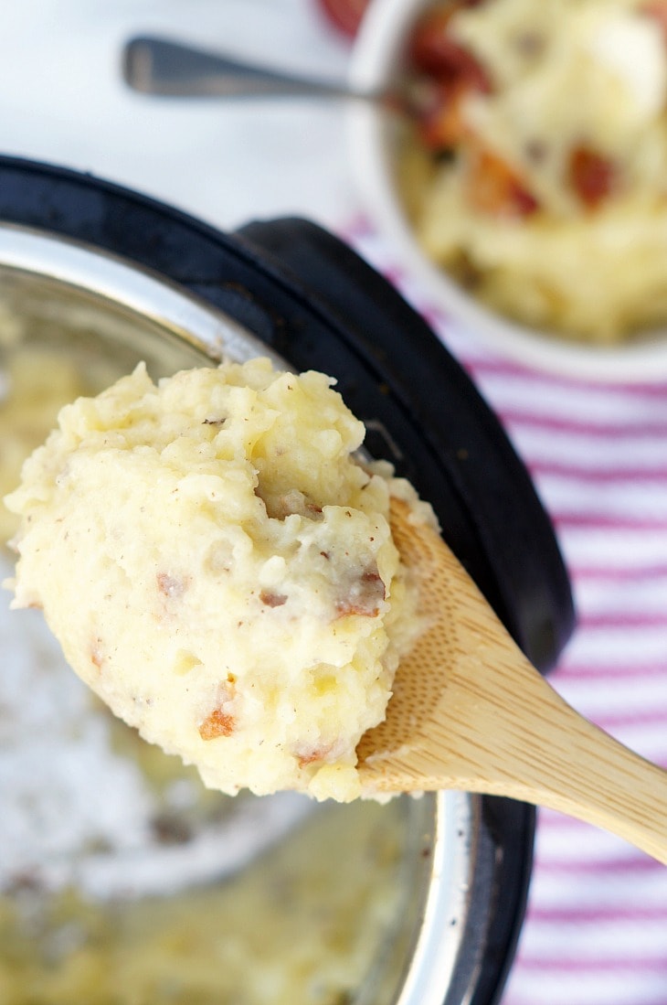 A wooden spoon with mashed potatoes and bacon 