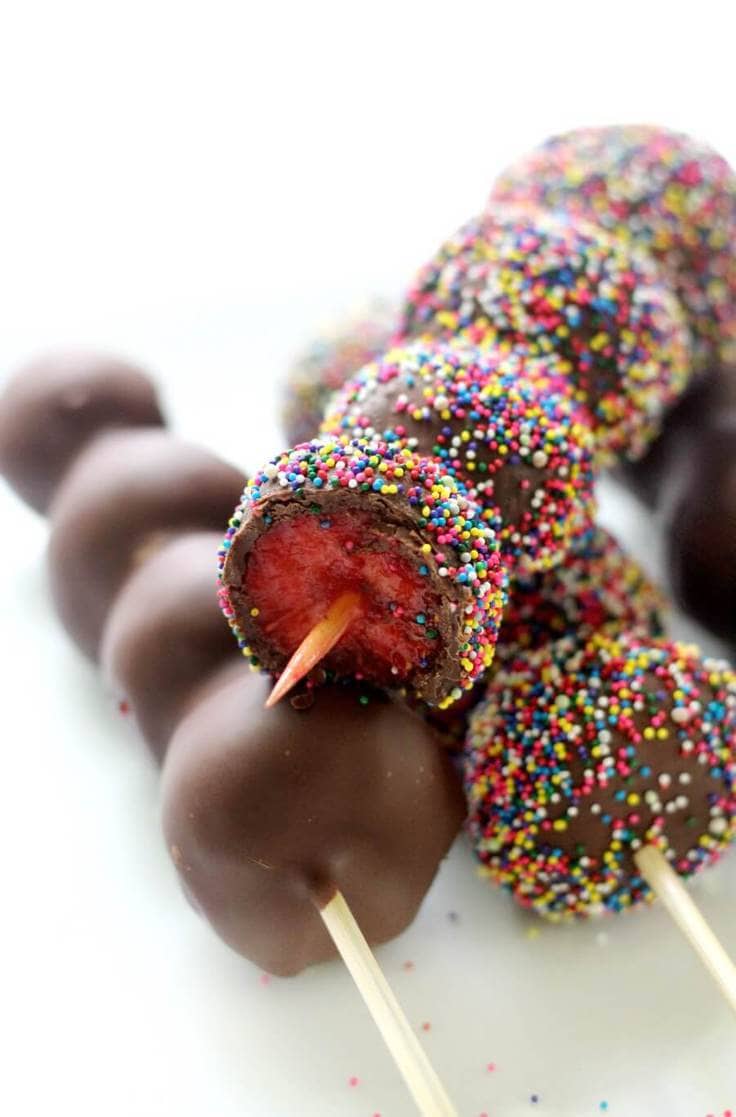Chocolate-covered strawberries on a stick with rainbow sprinkles
