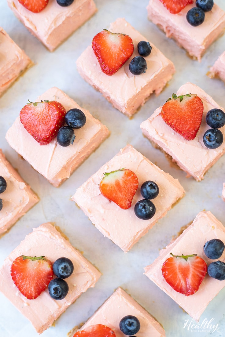 Pink no-bake strawberry cheesecake bars topped with fresh fruit