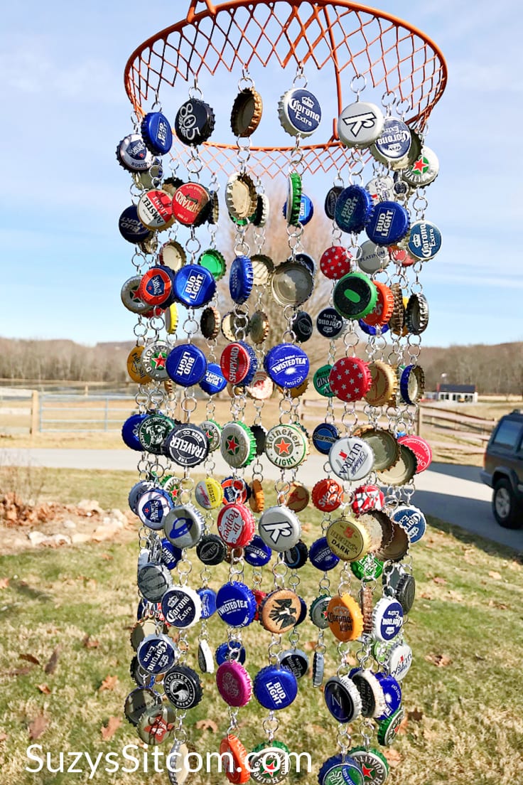 A wind chime made out of assorted colorful bottle caps hanging outdoors.