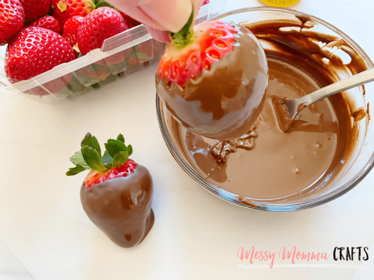 Dipping strawberries in melted chocolate.
