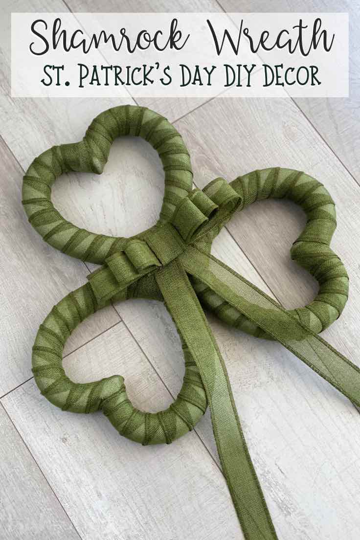 Green Shamrock wreath made from 3 heart shapes laying diagonal on a wood background.