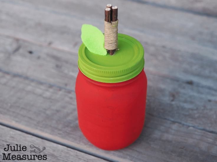 Mason jar painted to look like a red apple with a green lid.