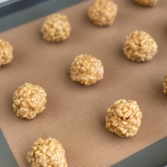 Prepared ball shaped Peanut Butter Rice Krispies Bites on a baking sheet.