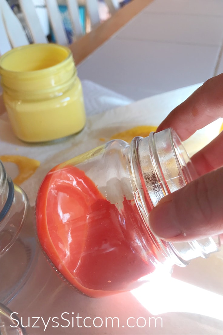 Swirling orange Mod Podge around the inside of a glass mason Jar