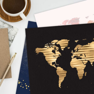 Preview of printable world map designs on desk with notebooks, pen and coffee mug.