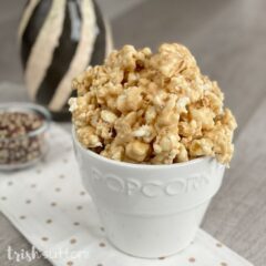 Caramel Marshmallow Popcorn Snack in a white popcorn jar with kernels in the background.
